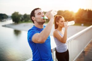 man and woman drinking water bottles