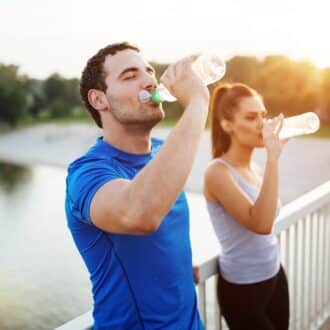 man and woman drinking water bottles