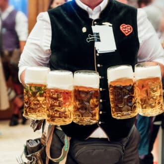 waiter carrying a lot of beer glasses in beer garden at Octoberfest in Munich