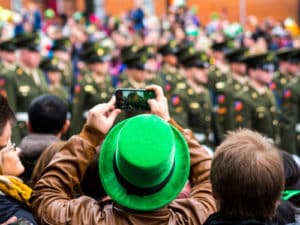Guy in green cap taking video in St. Patrick's day parade