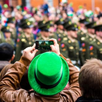 Guy in green cap taking video in St. Patrick's day parade