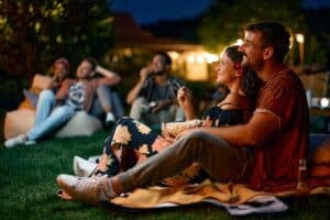Happy couple enjoying a movie night with friends in the backyard at Park Place Towers, Hartford CT, during an outdoor evening date